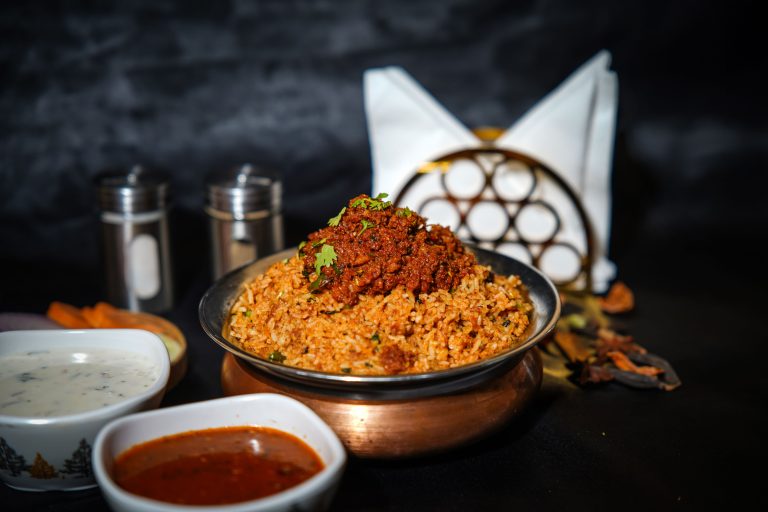 Aromatic biryani served in a copper bowl with spices and sauces. Perfect for food photography enthusiasts.