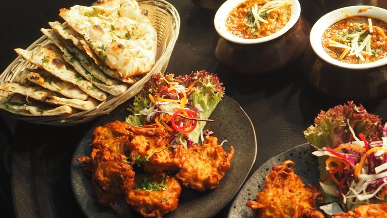 A delicious Indian food spread featuring curries, naan, and colorful salads, perfect for dinner.